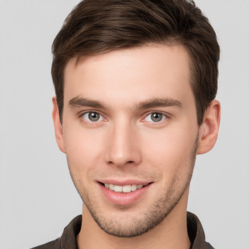 Joyful white young-adult male with short  brown hair and grey eyes