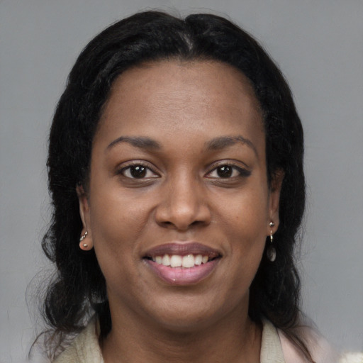 Joyful black young-adult female with long  brown hair and brown eyes