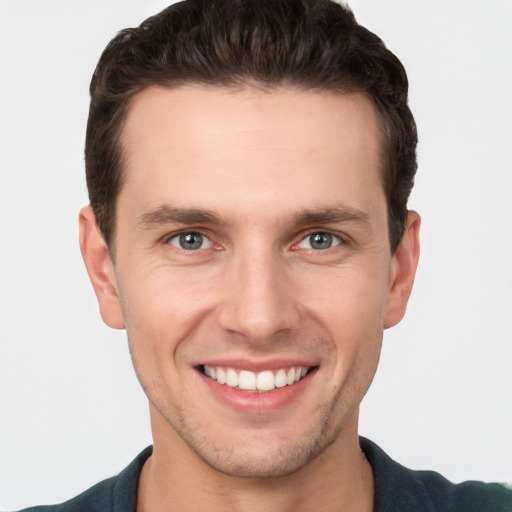 Joyful white young-adult male with short  brown hair and grey eyes