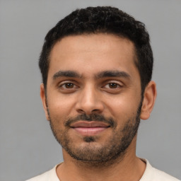 Joyful latino young-adult male with short  black hair and brown eyes