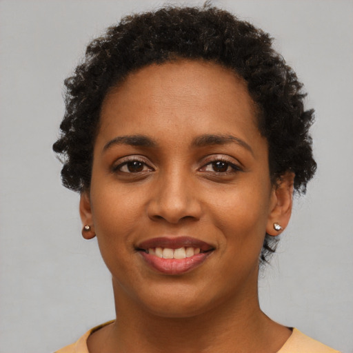 Joyful black young-adult female with short  black hair and brown eyes