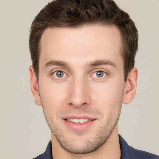 Joyful white young-adult male with short  brown hair and grey eyes