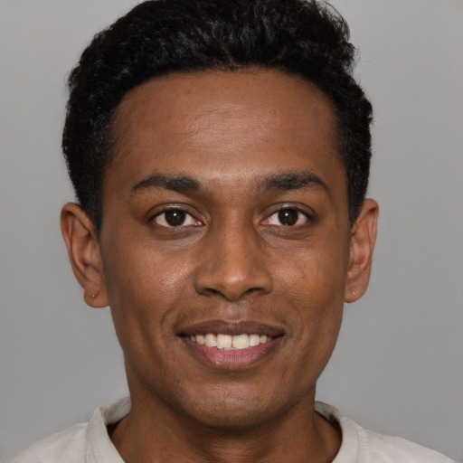 Joyful black young-adult male with short  black hair and brown eyes