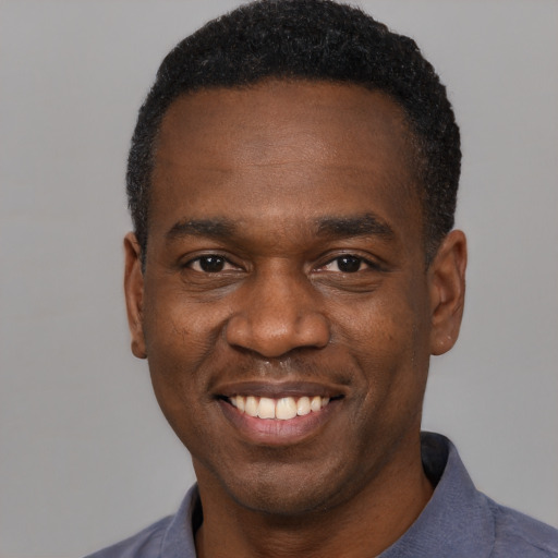 Joyful black young-adult male with short  black hair and brown eyes
