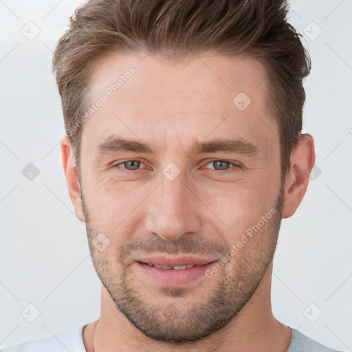 Joyful white young-adult male with short  brown hair and grey eyes