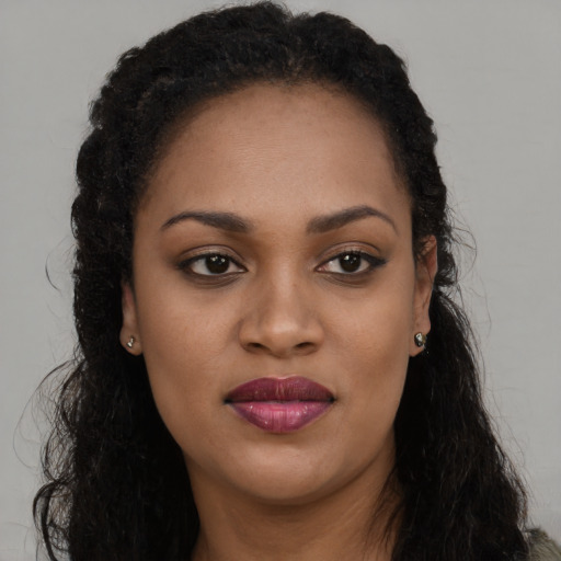 Joyful black young-adult female with long  brown hair and brown eyes
