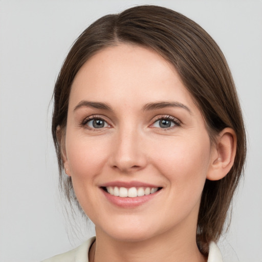 Joyful white young-adult female with medium  brown hair and grey eyes