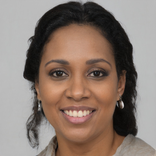 Joyful black young-adult female with long  brown hair and brown eyes
