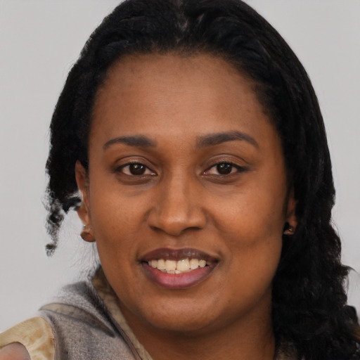 Joyful black young-adult female with long  black hair and brown eyes
