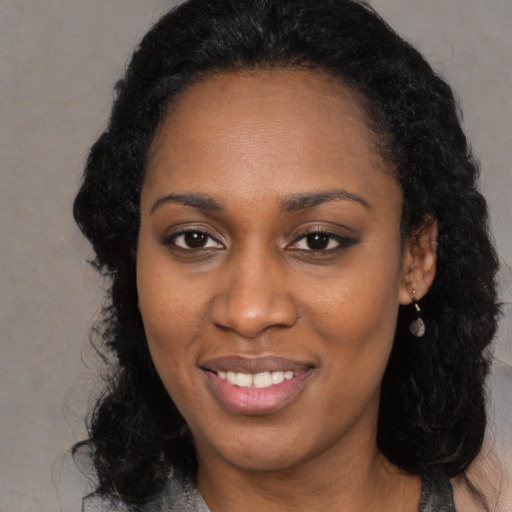 Joyful black young-adult female with long  black hair and brown eyes