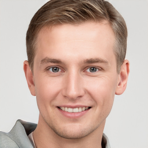 Joyful white young-adult male with short  brown hair and grey eyes