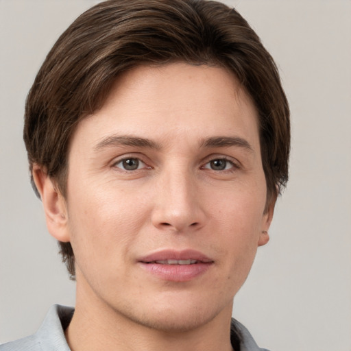 Joyful white young-adult male with short  brown hair and grey eyes