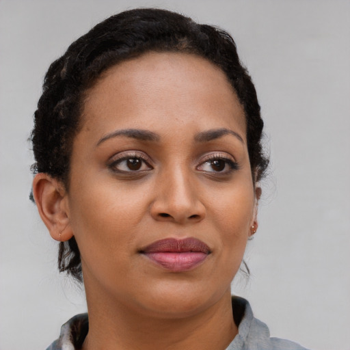 Joyful black young-adult female with long  brown hair and brown eyes
