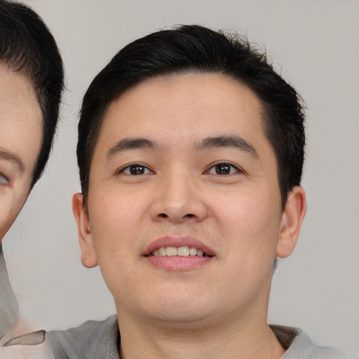 Joyful asian young-adult male with short  brown hair and brown eyes