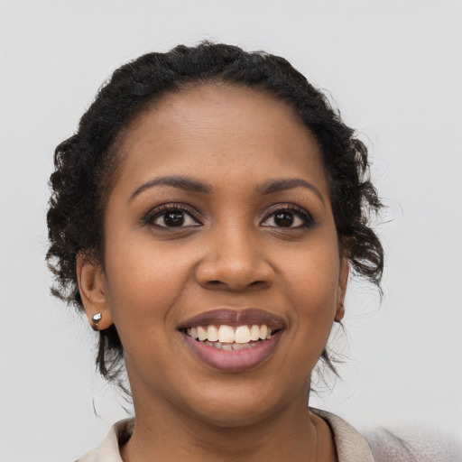 Joyful black young-adult female with long  black hair and brown eyes