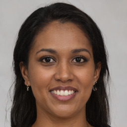 Joyful black young-adult female with long  brown hair and brown eyes