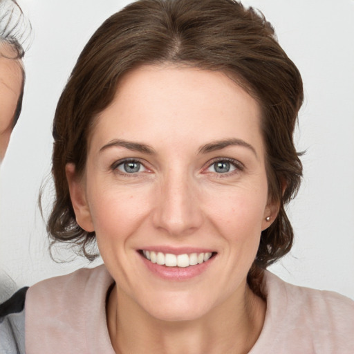 Joyful white young-adult female with medium  brown hair and grey eyes