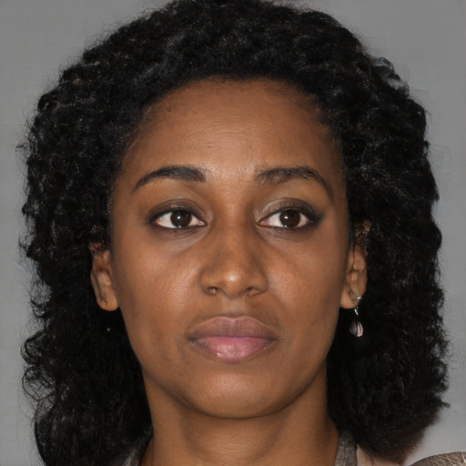 Joyful black young-adult female with long  black hair and brown eyes
