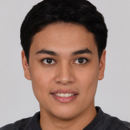 Joyful latino young-adult male with short  black hair and brown eyes