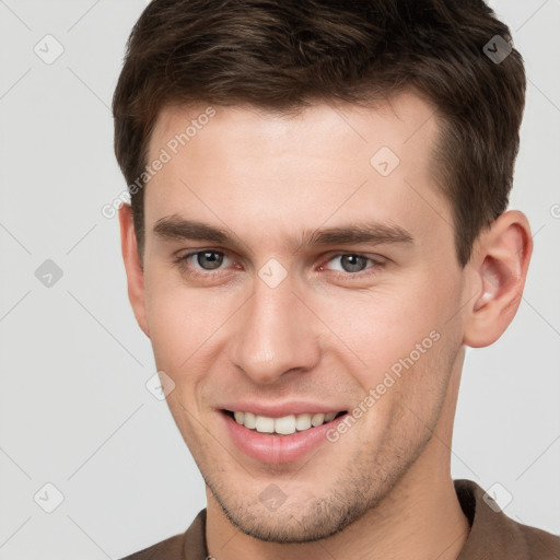 Joyful white young-adult male with short  brown hair and grey eyes