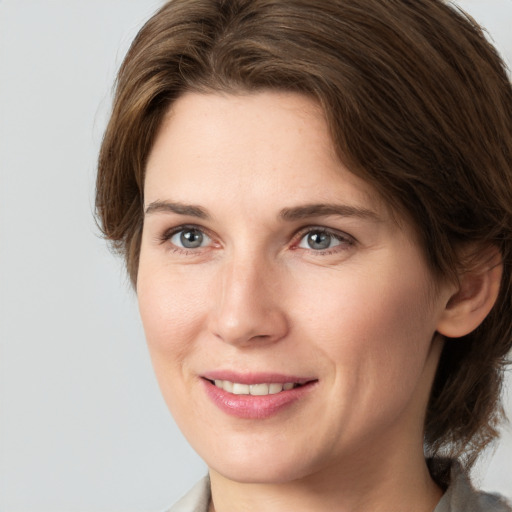 Joyful white young-adult female with medium  brown hair and grey eyes