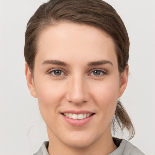 Joyful white young-adult female with medium  brown hair and grey eyes