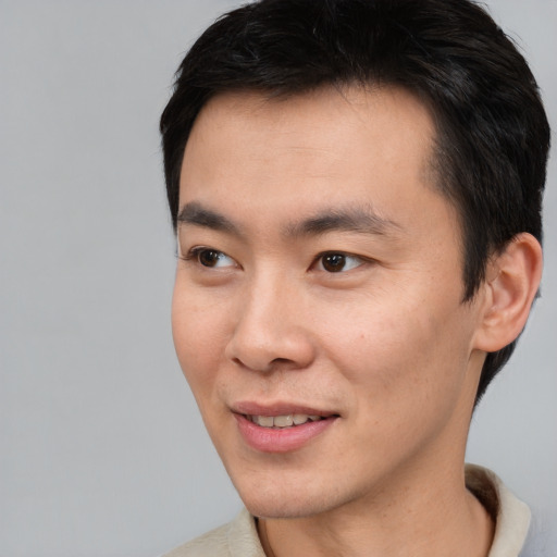 Joyful asian young-adult male with short  brown hair and brown eyes