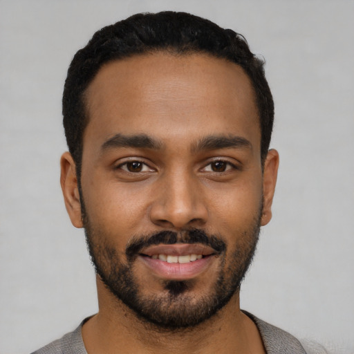 Joyful black young-adult male with short  black hair and brown eyes