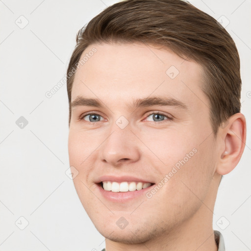 Joyful white young-adult male with short  brown hair and grey eyes