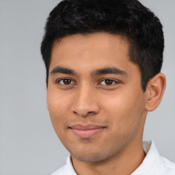 Joyful latino young-adult male with short  black hair and brown eyes