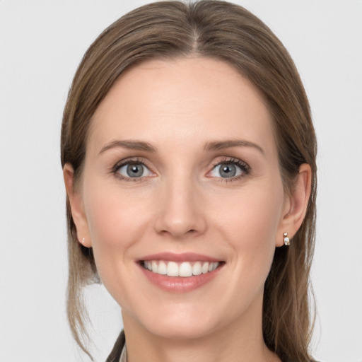 Joyful white young-adult female with medium  brown hair and grey eyes