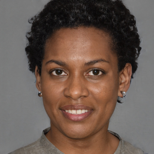 Joyful black young-adult female with short  black hair and brown eyes