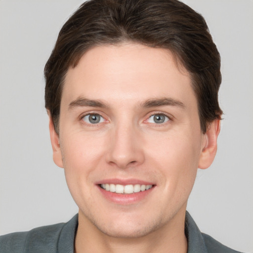 Joyful white young-adult male with short  brown hair and grey eyes