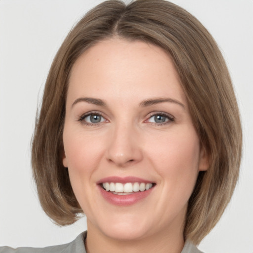 Joyful white young-adult female with medium  brown hair and grey eyes