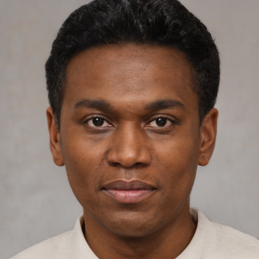 Joyful black young-adult male with short  black hair and brown eyes