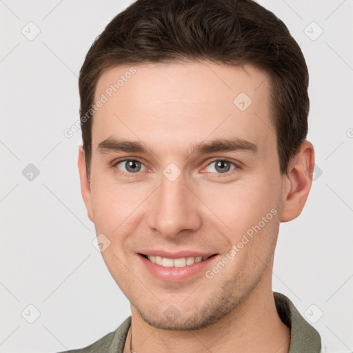 Joyful white young-adult male with short  brown hair and grey eyes