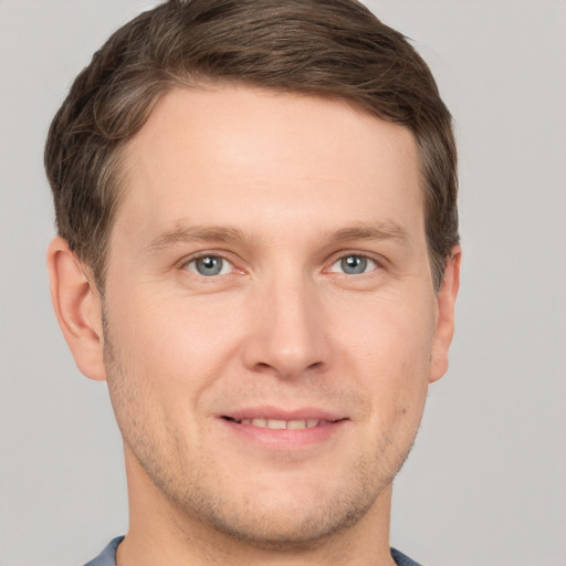 Joyful white young-adult male with short  brown hair and grey eyes