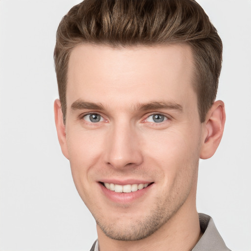 Joyful white young-adult male with short  brown hair and grey eyes