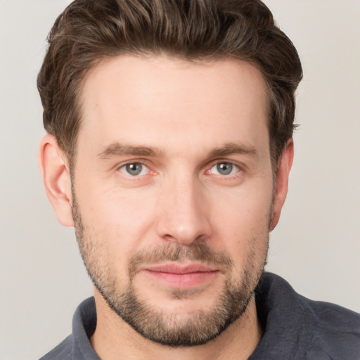 Joyful white young-adult male with short  brown hair and grey eyes