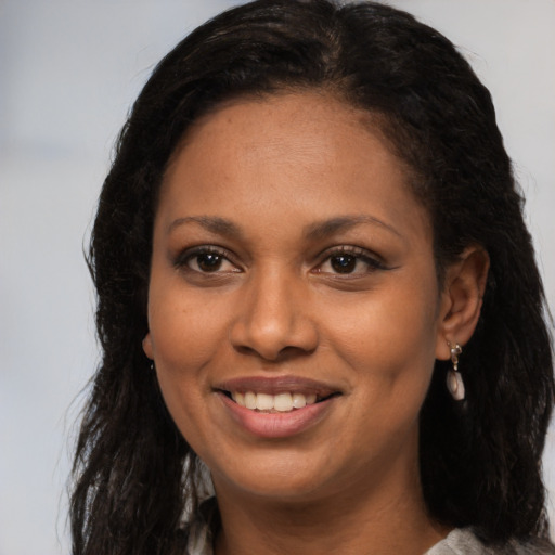 Joyful black young-adult female with long  brown hair and brown eyes