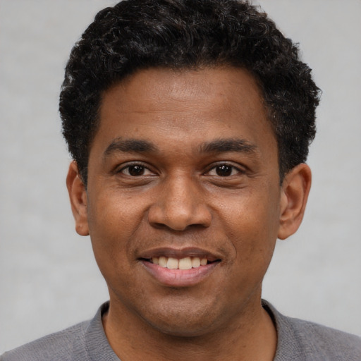 Joyful black young-adult male with short  black hair and brown eyes
