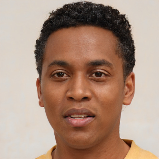Joyful black young-adult male with short  black hair and brown eyes