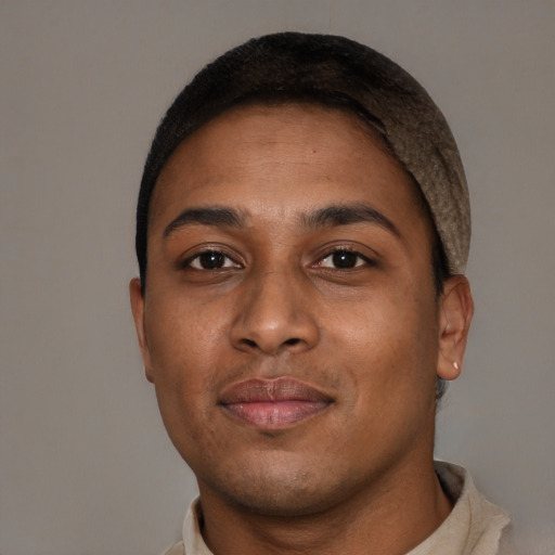 Joyful black young-adult male with short  brown hair and brown eyes