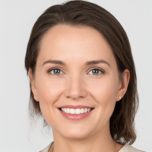 Joyful white young-adult female with medium  brown hair and grey eyes