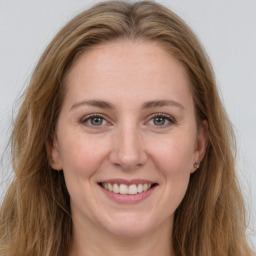 Joyful white young-adult female with long  brown hair and grey eyes