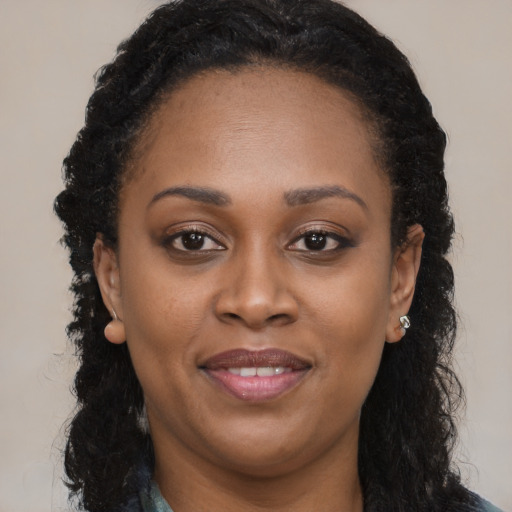 Joyful black young-adult female with long  brown hair and brown eyes
