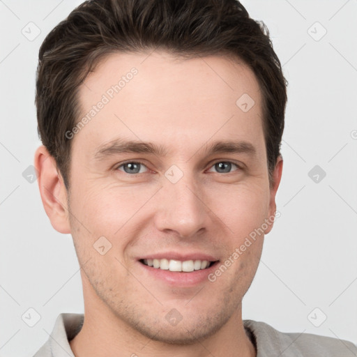 Joyful white young-adult male with short  brown hair and grey eyes