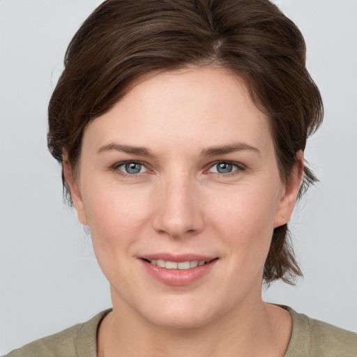 Joyful white young-adult female with medium  brown hair and grey eyes