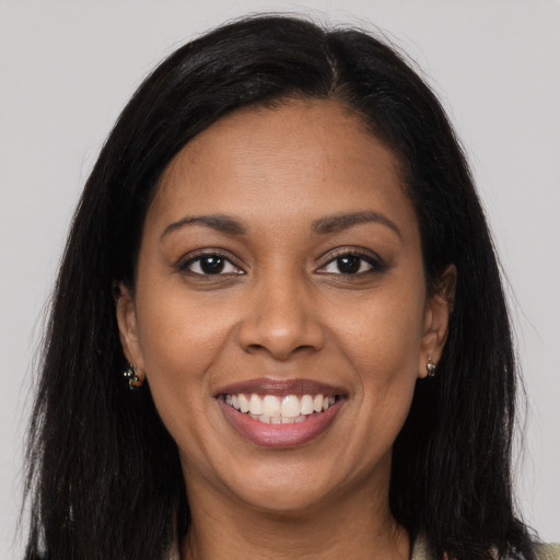 Joyful black young-adult female with long  brown hair and brown eyes