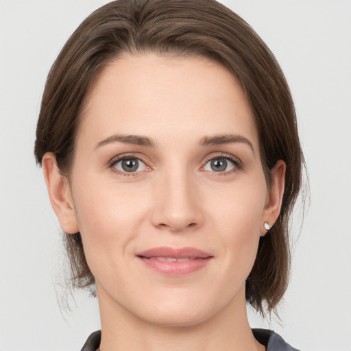 Joyful white young-adult female with medium  brown hair and grey eyes